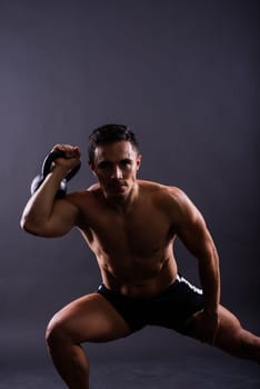 Strong young muscular focused fit man with a big muscles holding heavy kettlebells