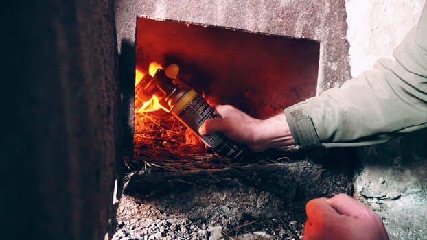 The guy lights a fire in the oven. To lay firewood. An old stove in an abandoned hut. Rusty metal doors. Dirty dusty walls. Firewood and fuel briquettes are burning. Heat from the oven.