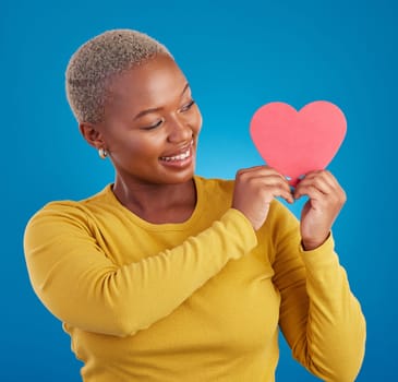 Paper, heart and happy with black woman in studio for love, date and kindness. Invitation, romance and feelings with female and shape isolated on blue background for emotion, support and affectionate.