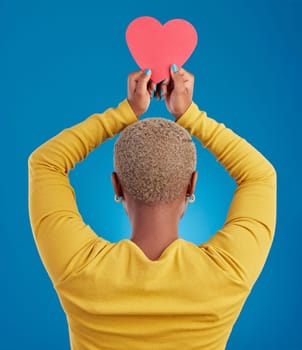 Paper, heart and back of black woman in studio for love, date and kindness. Invitation, romance and feelings with female and shape isolated on blue background for emotion, support and affectionate.