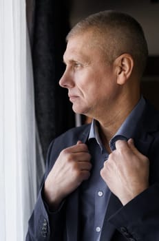 Portrait of a businessman looking out the window, holding on to his collar.