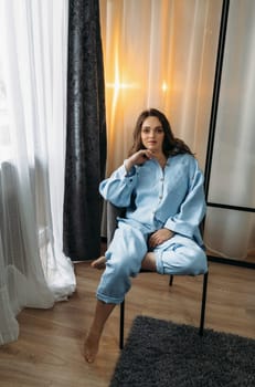 Portrait of a beautiful woman in a light blue suit, who is sitting in a chair. Vertical frame.
