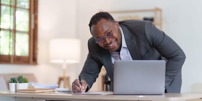 Smiling American African makes financial report and studies annual figures, analyzes profits. Accountant checks status of financial.