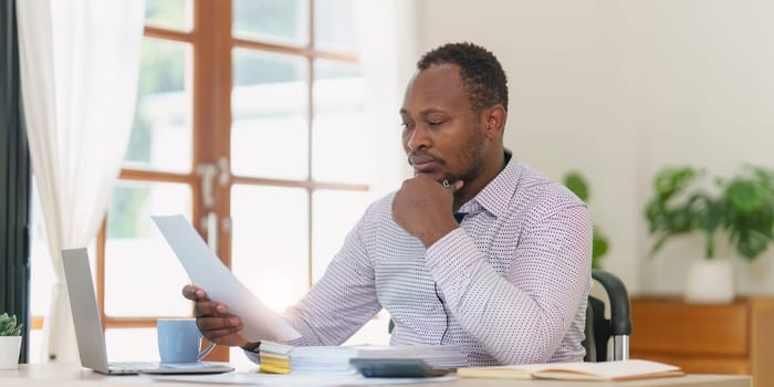 Smiling American African makes financial report and studies annual figures, analyzes profits. Accountant checks status of financial.