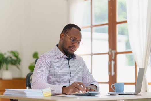 Smiling American African makes financial report and studies annual figures, analyzes profits. Accountant checks status of financial.