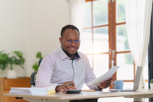 Smiling American African makes financial report and studies annual figures, analyzes profits. Accountant checks status of financial.