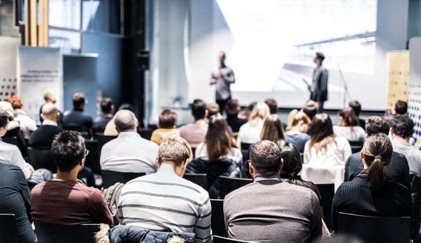 Speaker giving a talk in conference hall at business event. Audience at the conference hall. Business and Entrepreneurship concept. Focus on unrecognizable people in audience.