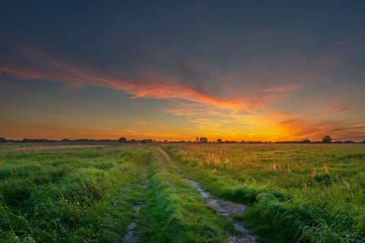 Dirt road through green meadows and beautiful sunset, Czulczyce, Poland