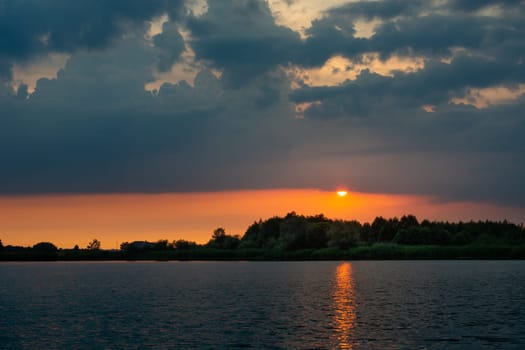Sunset with dark clouds over the calm lake