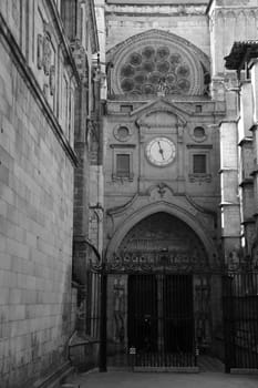 Vertical black and white shot of a side entrance of the Primatial Cathedral of Saint Mary of Toledo