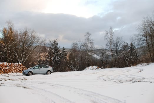 Ice blue car driving on a trail through a snowy white forest in Harz mountains, Germany