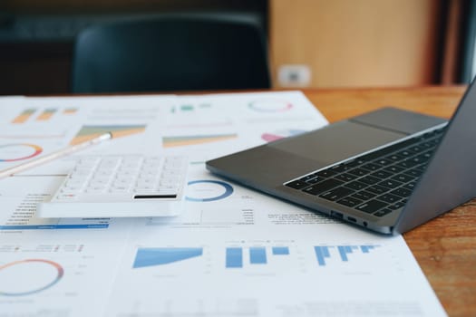 computer, calculator, budget and finance documents and pen on wooden desk.