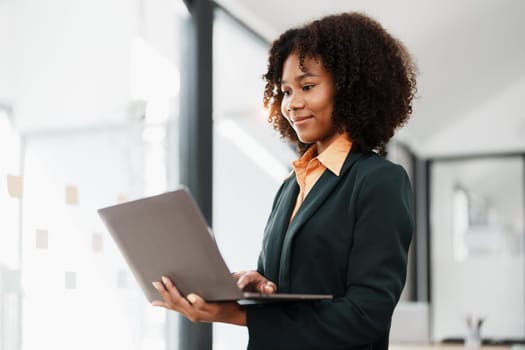 Beautiful young teen American African holding computer laptop with planning working on financial document, tax, exchange, accounting and Financial advisor.