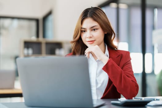 Beautiful young teen asian businesswoman using computer laptop and calculator for calculate with planning working on financial document, tax, exchange, accounting and Financial advisor.