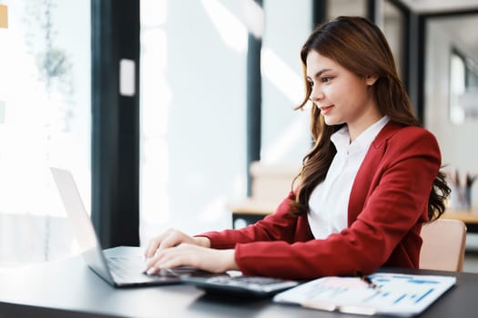 Beautiful young teen asian businesswoman using computer laptop and calculator for calculate with planning working on financial document, tax, exchange, accounting and Financial advisor.