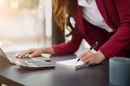 Beautiful young teen asian businesswoman using laptop computer and paperworks with planning working on financial document, tax, exchange, accounting and Financial advisor.