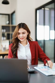 Beautiful young teen asian businesswoman using laptop computer and paperworks with planning working on financial document, tax, exchange, accounting and Financial advisor.