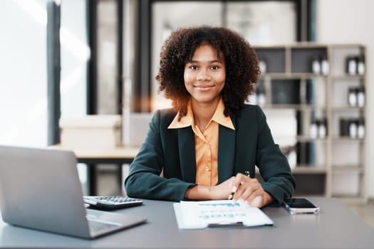 Beautiful young teen American African holding computer laptop with planning working on financial document, tax, exchange, accounting and Financial advisor.