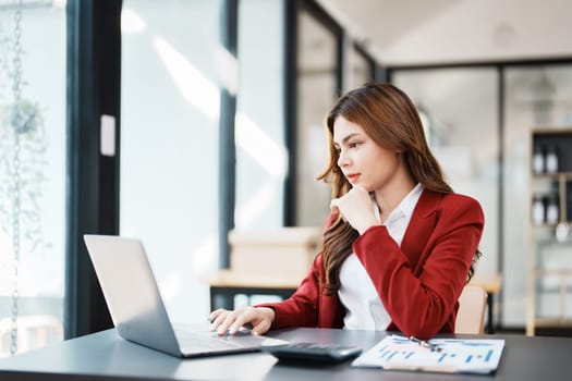 Beautiful young teen asian businesswoman using computer laptop and calculator for calculate with planning working on financial document, tax, exchange, accounting and Financial advisor.