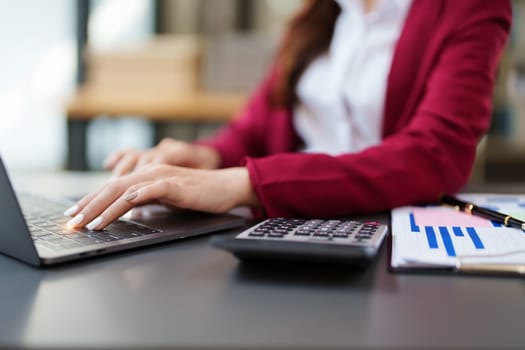 Beautiful young teen asian businesswoman using computer laptop and calculator for calculate with planning working on financial document, tax, exchange, accounting and Financial advisor.