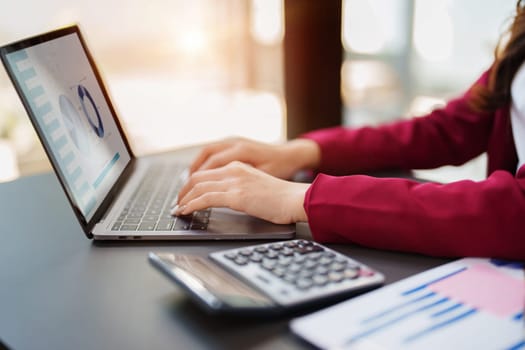 Beautiful young teen asian businesswoman using computer laptop and calculator for calculate with planning working on financial document, tax, exchange, accounting and Financial advisor.