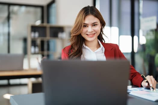 Beautiful young teen asian businesswoman using laptop computer and paperworks with planning working on financial document, tax, exchange, accounting and Financial advisor.