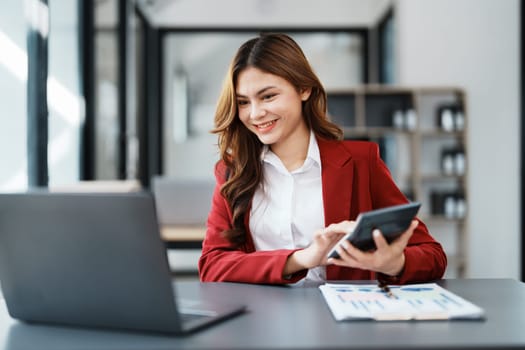 Beautiful young teen asian businesswoman using computer laptop and calculator for calculate with planning working on financial document, tax, exchange, accounting and Financial advisor.