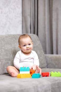 cute baby girl playing with colorful toy blocks at home
