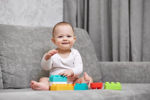 cute baby girl playing with colorful toy blocks at home. Early development for kids.