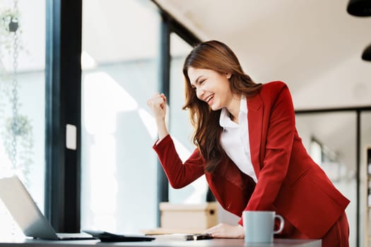 Beautiful young teen asian businesswomen using computer laptop with hands up in winner is gesture, Happy to be successful celebrating achievement success.