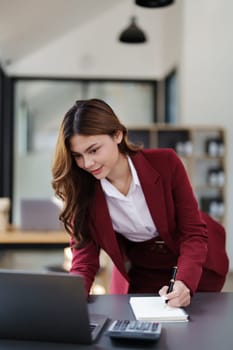 Beautiful young teen asian businesswoman using laptop computer and paperworks with planning working on financial document, tax, exchange, accounting and Financial advisor.