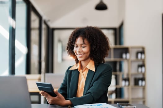 Beautiful young teen American African using calculator for calculating and computer laptop with planning working on financial document, tax, exchange, accounting and Financial advisor.