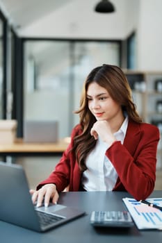 Beautiful young teen asian businesswoman using computer laptop and calculator for calculate with planning working on financial document, tax, exchange, accounting and Financial advisor.