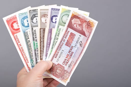 Old Bolivian money - Bolivianos in the hand on a gray background