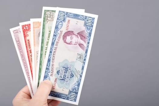 Old Chilean money - Escudos in the hand on a gray background	