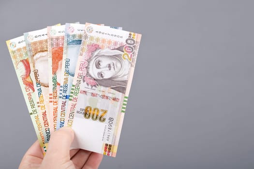 Peruvian money - Soles in the hand on a gray background