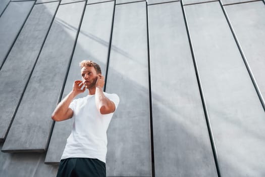 Takes a break. Young man in sportive clothes have workout outdoors at daytime.