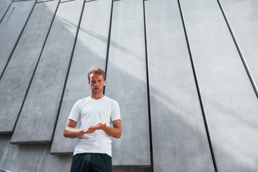 Takes a break. Young man in sportive clothes have workout outdoors at daytime.