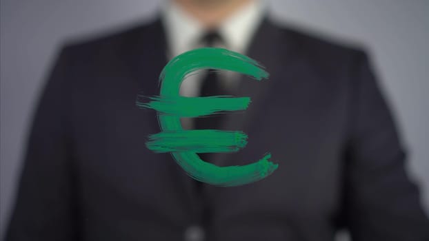 Businessman draws the euro symbol on the glass. A man in a suit draws on glass with a brush and green paint. 4k