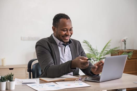 African American businessman using his laptop computer while working remotely from home. Online working or learning concept.