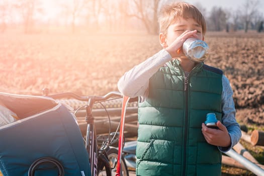 teenager boy with bicycle drinks water on sunny day