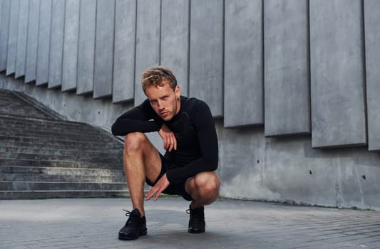 Young man in sportive clothes have workout outdoors at daytime.