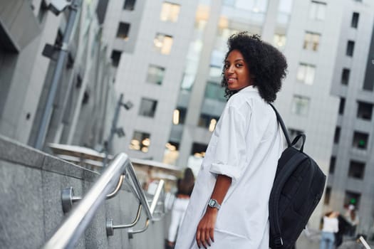 African american woman in good clothes is outdoors in the city at daytime.