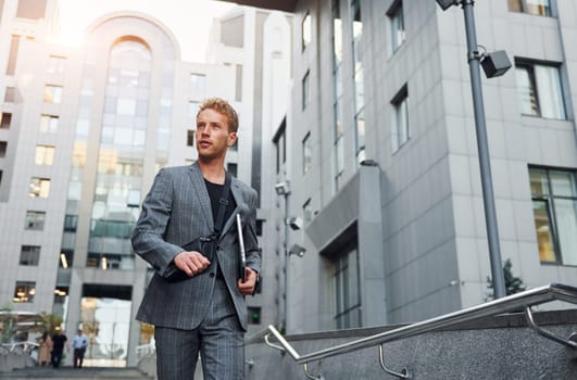 Young elegant man in good clothes is outdoors in the city at daytime.