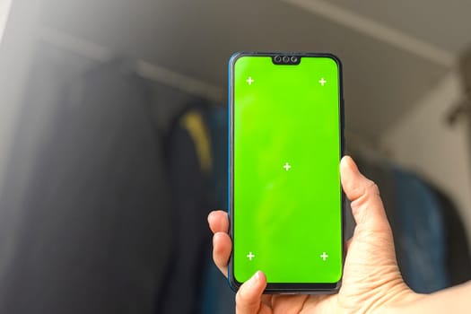 Smartphone with Chroma Key Green Screen close-up. Buying Used Second Hand recycled clothes. Home sale. Recycling Eco New Life, European Store.