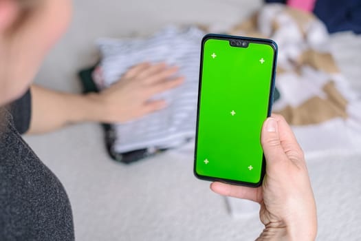 Smartphone with Chroma Key Green Screen close-up. Buying Used Second Hand recycled clothes. Home sale. Recycling Eco New Life, European Store.