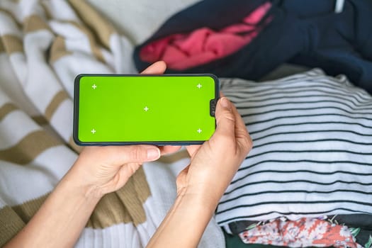 Smartphone with Chroma Key Green Screen close-up. Buying Used Second Hand recycled clothes. Home sale. Recycling Eco New Life, European Store.