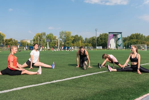 Female coach and group of children conducts a training session at the stadium outdoors