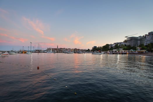 A very beautiful sunset on the pier, a beautiful sky in Budva, Montenegro against the backdrop of a pier with yachts and a resort town