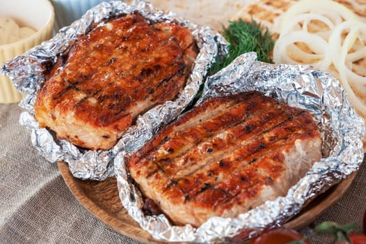 Grilled pork meat in foil with flapjack and vegetables. Summer rest concept